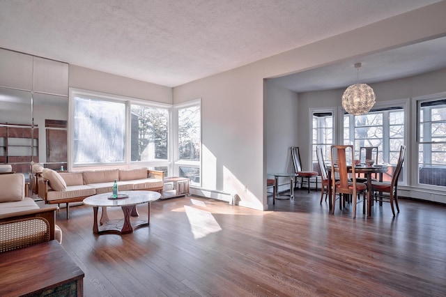 living room with a wealth of natural light, wood-type flooring, a textured ceiling, and a chandelier