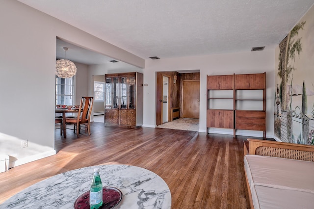 living room featuring wood-type flooring, a textured ceiling, and a notable chandelier