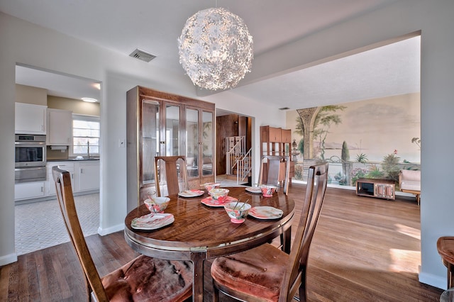 dining space featuring light wood-type flooring, a chandelier, and sink