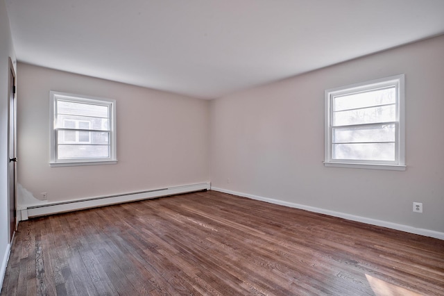 spare room featuring baseboard heating and wood-type flooring