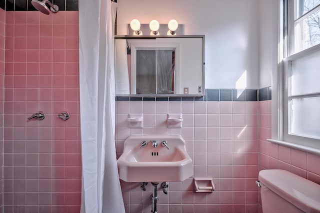 bathroom with sink, tile walls, toilet, and walk in shower