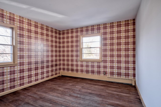 spare room featuring dark hardwood / wood-style flooring, a wealth of natural light, and a baseboard radiator