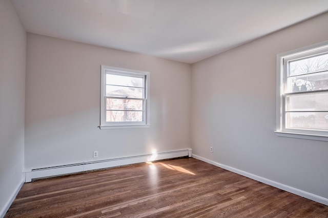 empty room with dark wood-type flooring, a healthy amount of sunlight, and a baseboard radiator