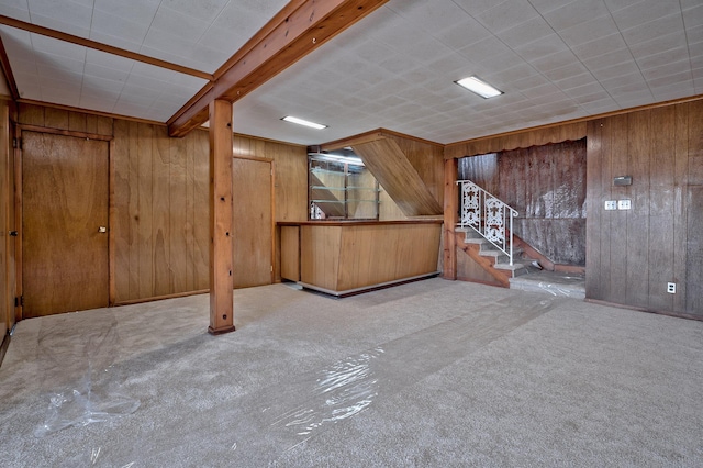 basement featuring light carpet and wood walls