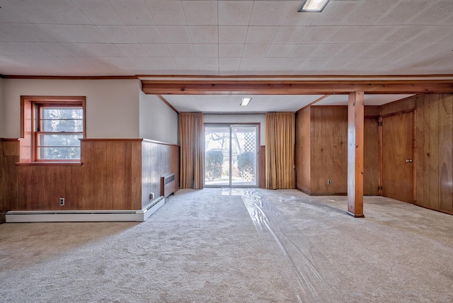 basement featuring baseboard heating, crown molding, light carpet, and wood walls