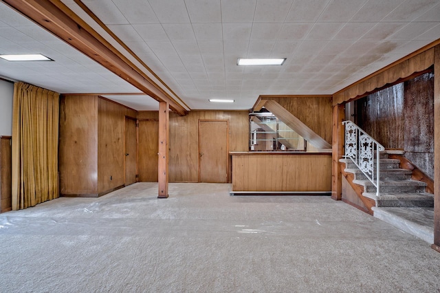 basement featuring light colored carpet and wood walls