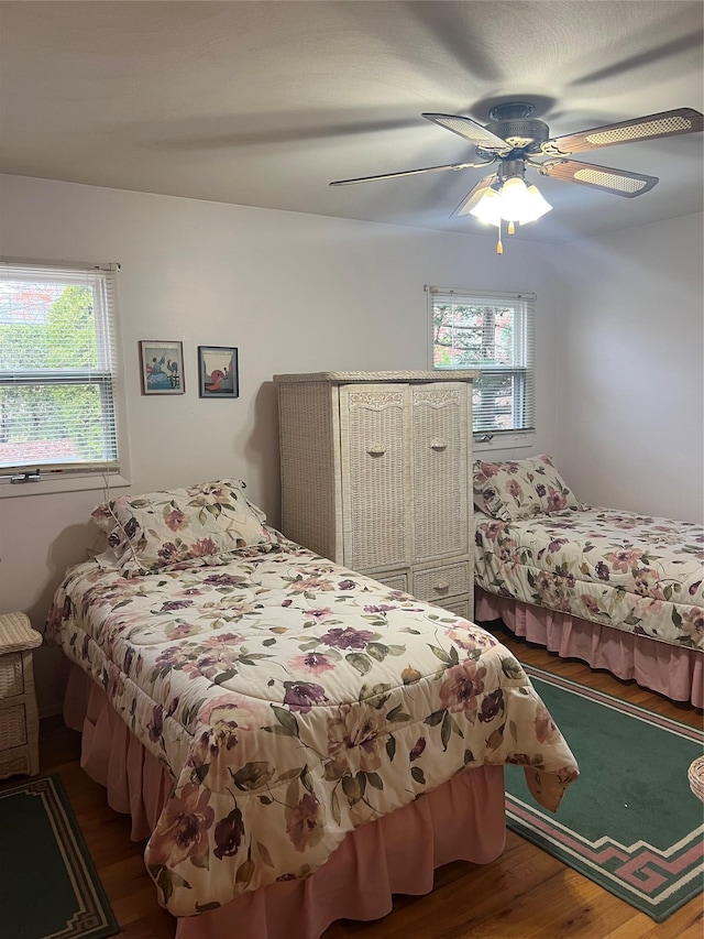 bedroom with multiple windows, wood-type flooring, and ceiling fan