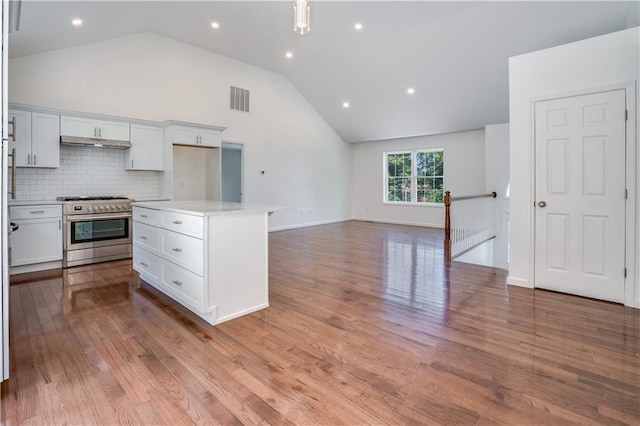 kitchen with a center island, stainless steel range, decorative backsplash, white cabinets, and light wood-type flooring