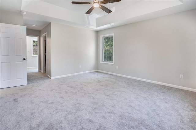 carpeted empty room featuring a raised ceiling and ceiling fan