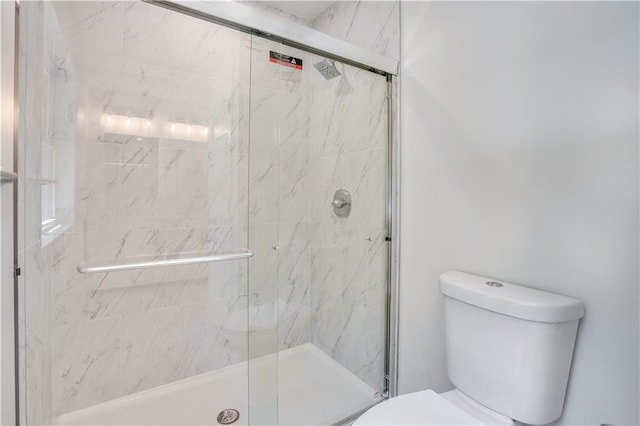 bathroom featuring toilet and a shower with door