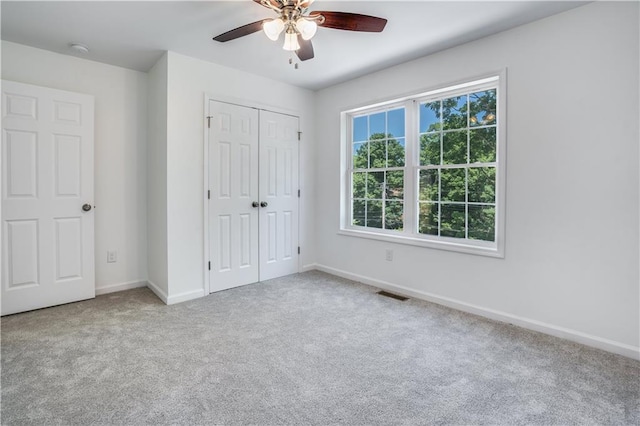 unfurnished bedroom with ceiling fan, a closet, and light carpet