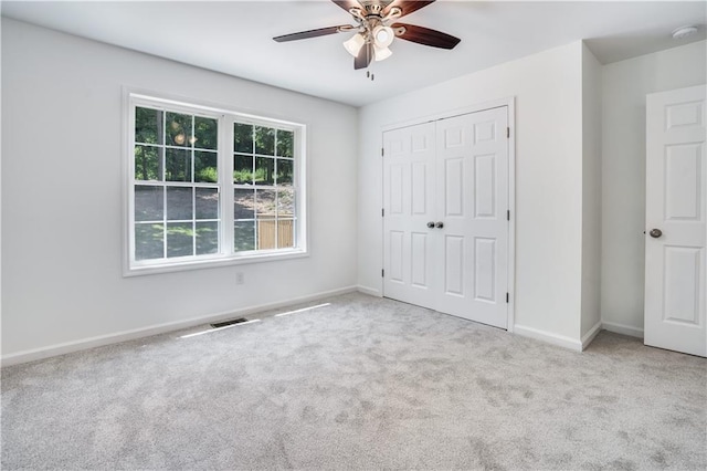 unfurnished bedroom featuring ceiling fan, a closet, and light carpet