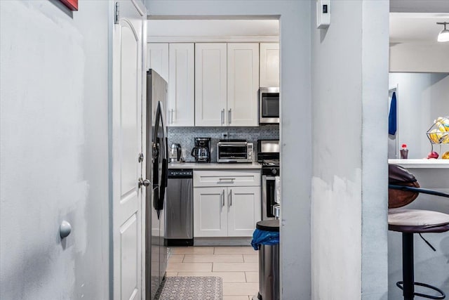 kitchen with backsplash, white cabinetry, and stainless steel appliances