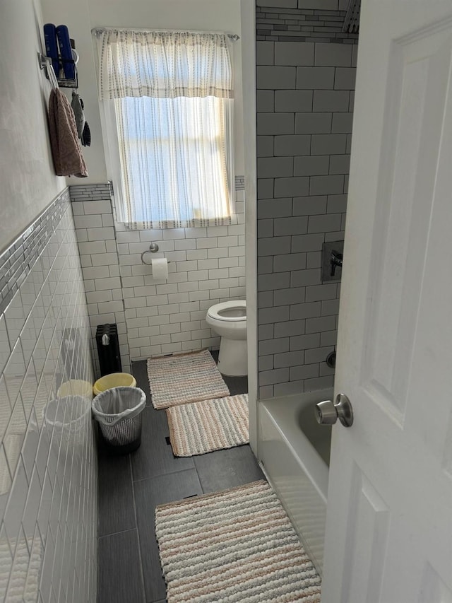 bathroom featuring tile patterned floors, toilet, and tile walls