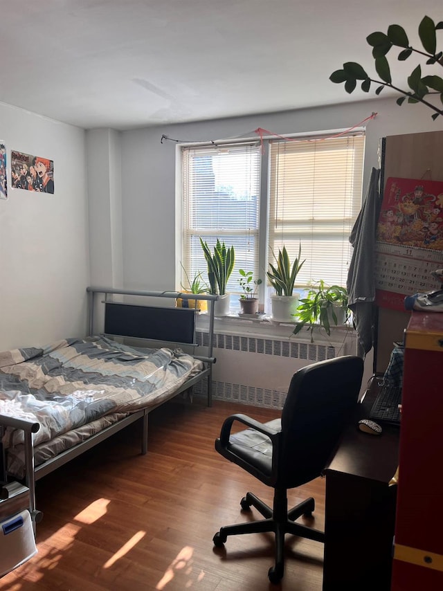 bedroom featuring hardwood / wood-style floors and radiator heating unit