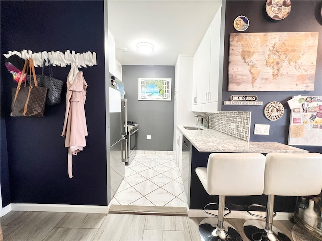 kitchen featuring appliances with stainless steel finishes, tasteful backsplash, sink, light hardwood / wood-style floors, and white cabinetry