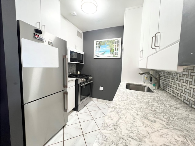 kitchen featuring decorative backsplash, appliances with stainless steel finishes, white cabinetry, and sink