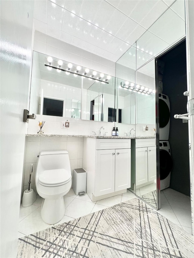 bathroom with tile patterned floors, vanity, tile walls, and stacked washer and clothes dryer