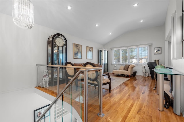 living room with a chandelier, light hardwood / wood-style flooring, and lofted ceiling