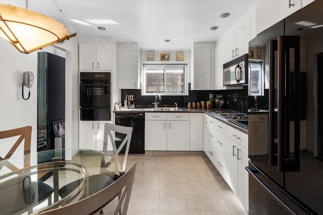 kitchen featuring backsplash, black appliances, sink, light tile patterned floors, and white cabinetry