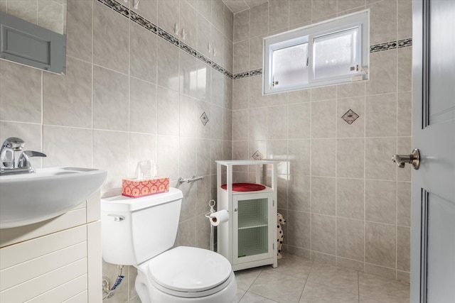 bathroom with toilet, vanity, tile patterned floors, and tile walls