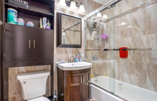 full bathroom with vanity, combined bath / shower with glass door, tile walls, and toilet