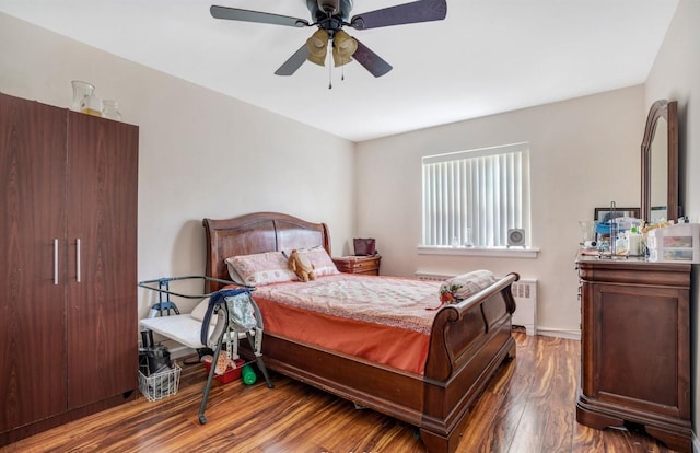 bedroom with ceiling fan, radiator heating unit, and wood-type flooring