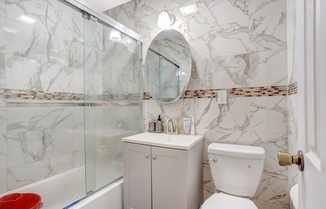 full bathroom with vanity, toilet, bath / shower combo with glass door, and tile walls