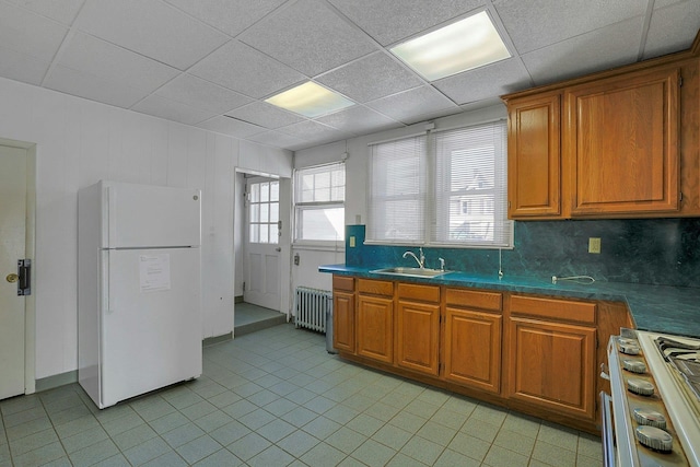 kitchen featuring decorative backsplash, a paneled ceiling, radiator, white appliances, and sink