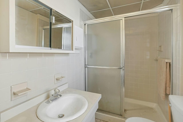 bathroom with tasteful backsplash, an enclosed shower, vanity, tile walls, and toilet