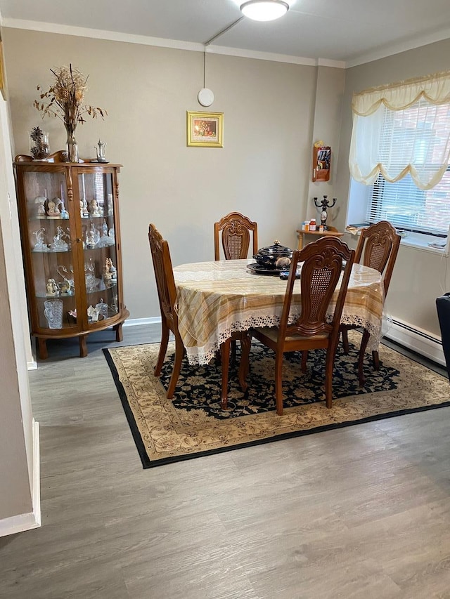 dining area featuring wood-type flooring, a baseboard radiator, and crown molding