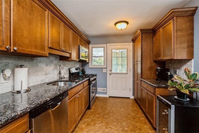 kitchen with sink, stainless steel appliances, dark stone countertops, and decorative backsplash