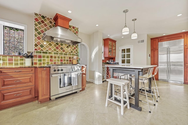 kitchen featuring a breakfast bar, decorative light fixtures, high quality appliances, light stone countertops, and backsplash