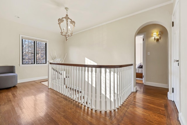 hall featuring an inviting chandelier, ornamental molding, and wood-type flooring