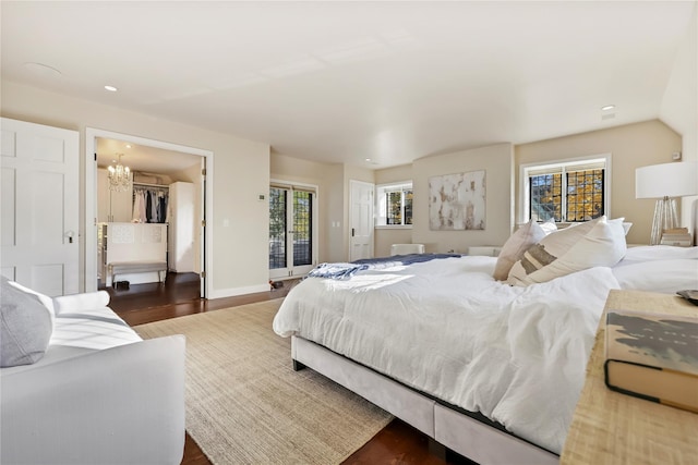 bedroom featuring multiple windows, access to exterior, dark hardwood / wood-style flooring, and a chandelier