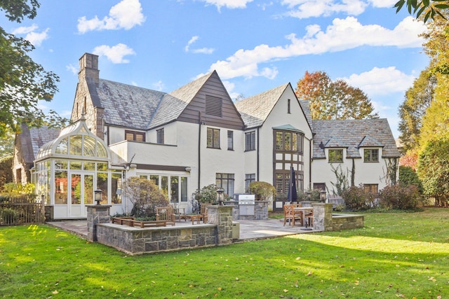 back of house featuring exterior kitchen, a patio, and a lawn