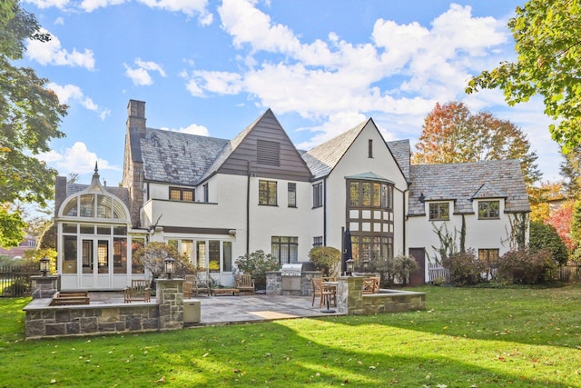 back of house with exterior kitchen, a patio, a sunroom, and a yard