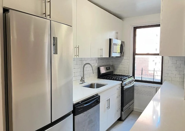 kitchen with decorative backsplash, stainless steel appliances, white cabinetry, and sink