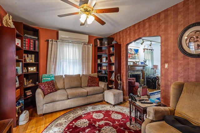 living room with ceiling fan, light hardwood / wood-style floors, and an AC wall unit