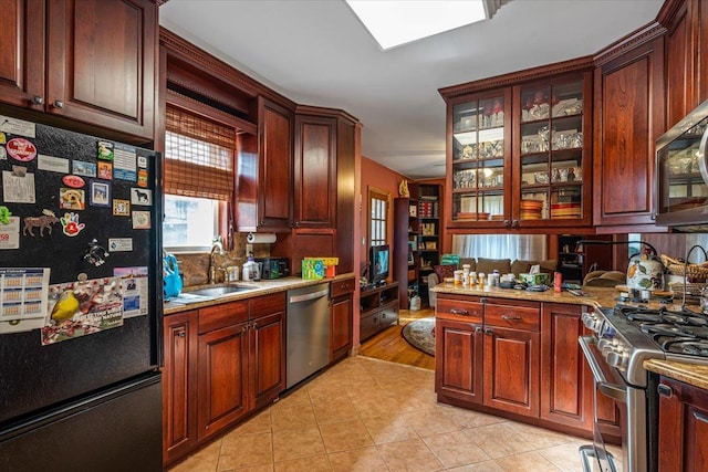 kitchen featuring light stone counters, sink, light wood-type flooring, and appliances with stainless steel finishes