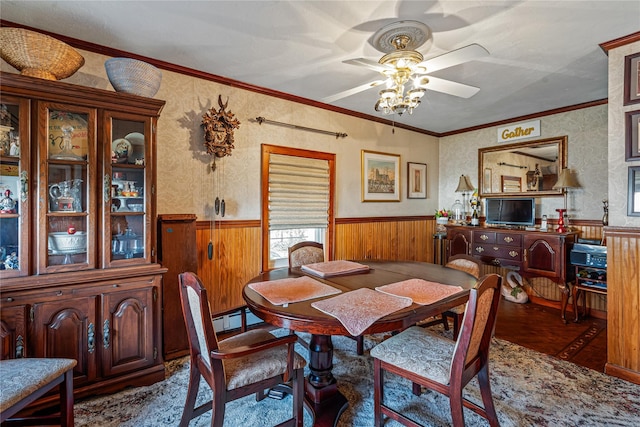 dining room with ceiling fan, baseboard heating, crown molding, and wooden walls