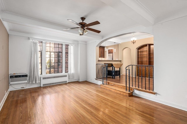 empty room featuring crown molding, radiator heating unit, ceiling fan with notable chandelier, and hardwood / wood-style flooring