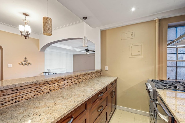 kitchen with light stone countertops, ceiling fan, stainless steel gas range oven, crown molding, and pendant lighting