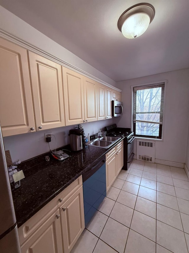 kitchen featuring radiator heating unit, sink, stainless steel appliances, dark stone countertops, and light tile patterned flooring