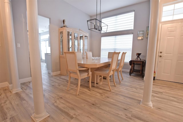 dining area featuring decorative columns, an inviting chandelier, and light wood-type flooring