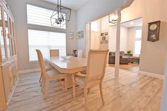 dining room featuring ornate columns, a wealth of natural light, and light hardwood / wood-style floors