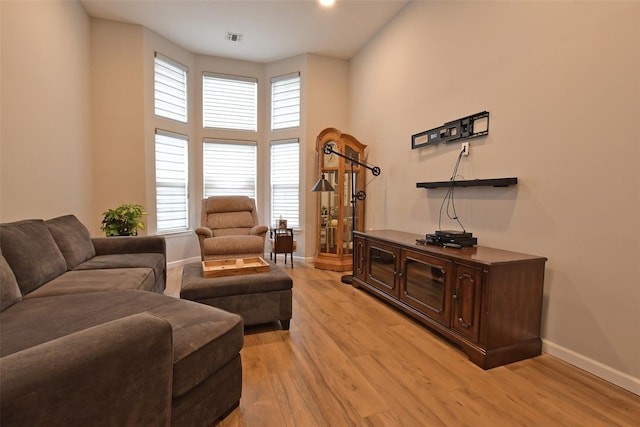 living room with plenty of natural light, a high ceiling, and light hardwood / wood-style flooring