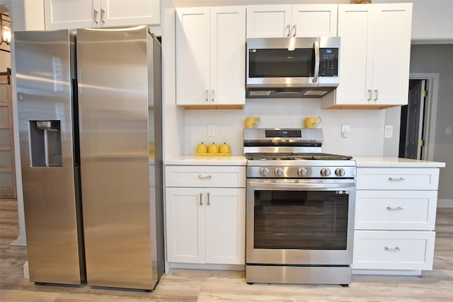 kitchen with white cabinets, appliances with stainless steel finishes, backsplash, and light hardwood / wood-style flooring