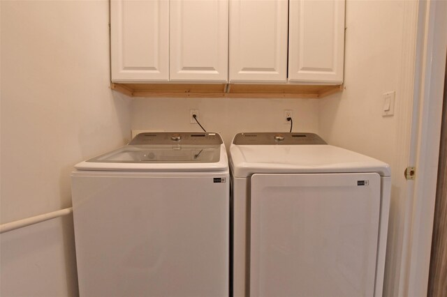 clothes washing area with washing machine and clothes dryer and cabinets