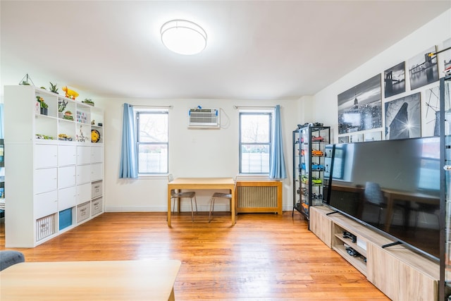 misc room featuring an AC wall unit, a wealth of natural light, radiator heating unit, and light hardwood / wood-style floors